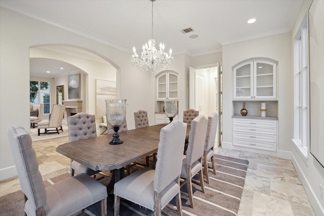 dining area with arched walkways, stone tile flooring, crown molding, and baseboards