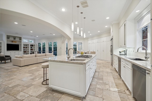 kitchen featuring stainless steel appliances, stone tile flooring, a sink, and ornamental molding