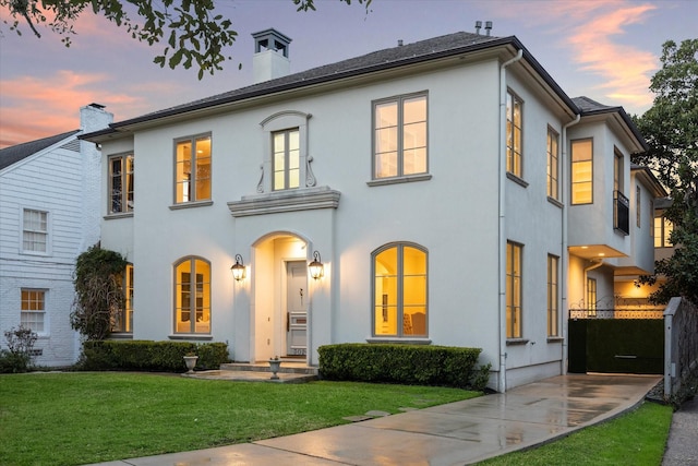 view of front of property with a lawn, a chimney, and stucco siding