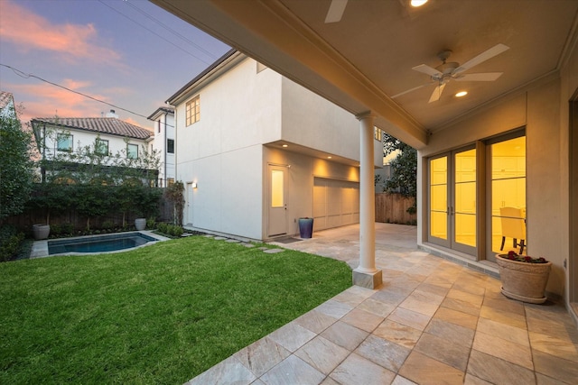 yard at dusk featuring a patio area, fence, a ceiling fan, and a fenced in pool