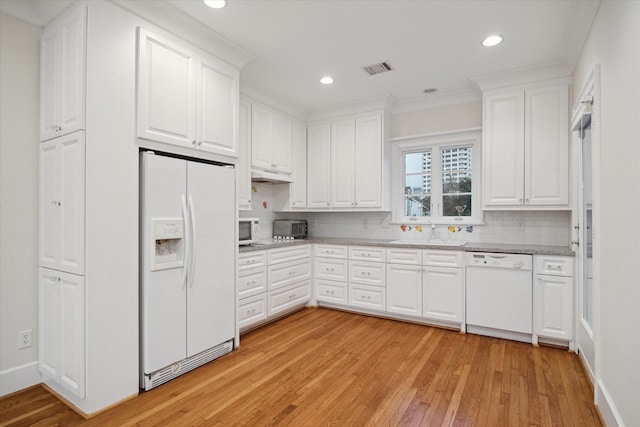 kitchen with white appliances, decorative backsplash, a sink, and white cabinets