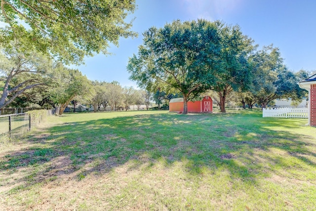 view of yard featuring an outbuilding, fence, and a shed