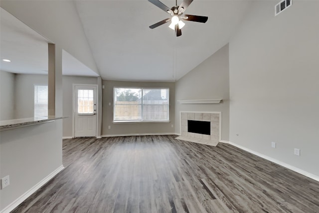 unfurnished living room with baseboards, visible vents, a tile fireplace, lofted ceiling, and wood finished floors