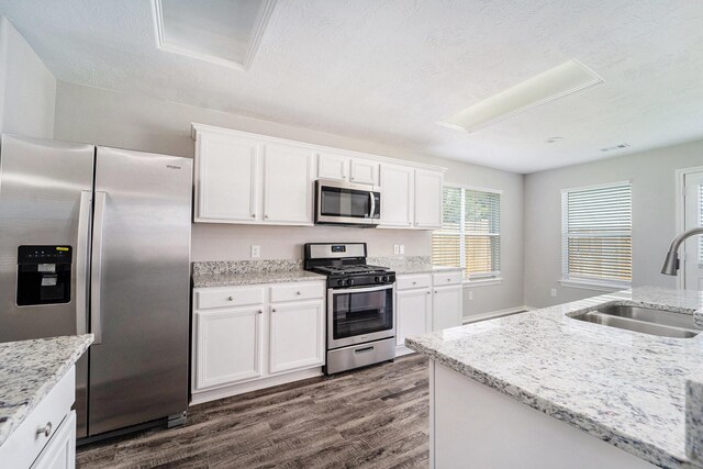 1911 Arrow Star Ct, Katy, TX 77493 - kitchen with appliances with stainless steel finishes, dark wood-type flooring, white cabinets, light stone counters, and a textured ceiling