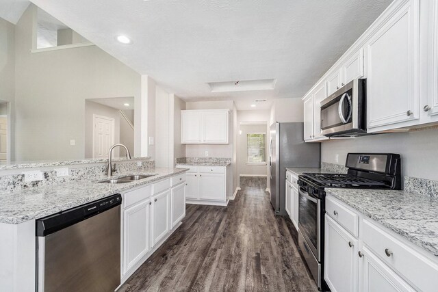 1911 Arrow Star Ct, Katy, TX 77493 - kitchen with stainless steel appliances, white cabinets, dark wood-style floors, light stone counters, and a center island with sink