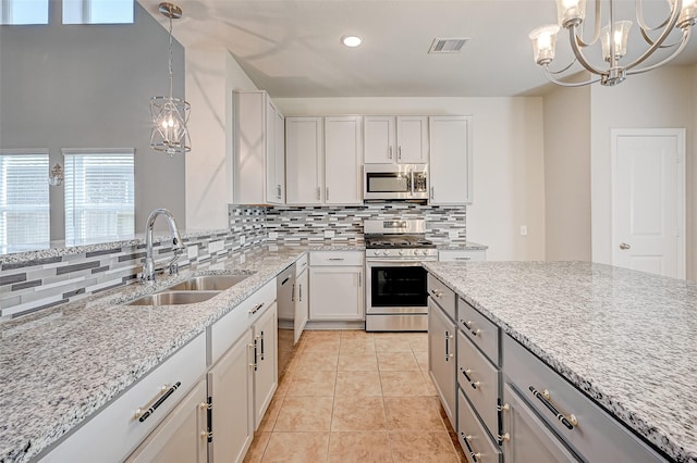 kitchen with light stone counters, stainless steel appliances, a sink, visible vents, and backsplash