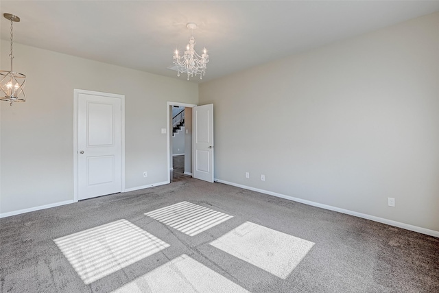 unfurnished room with baseboards, carpet flooring, and a notable chandelier