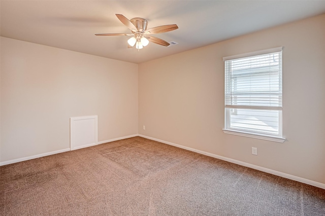 carpeted spare room featuring visible vents, ceiling fan, and baseboards