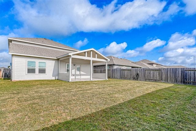 back of house with a yard, a patio, a fenced backyard, and roof with shingles