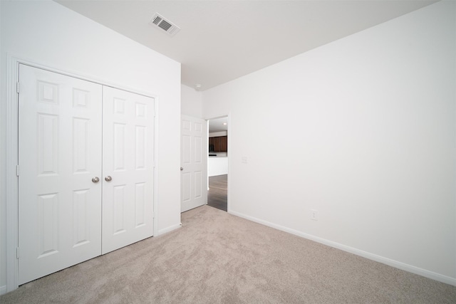 unfurnished bedroom featuring a closet, carpet, visible vents, and baseboards