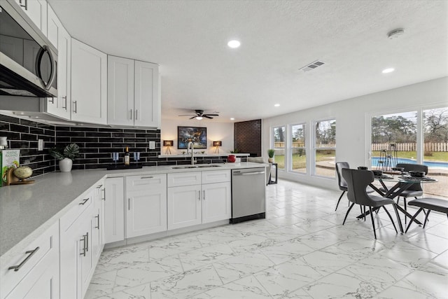 kitchen with marble finish floor, visible vents, appliances with stainless steel finishes, a sink, and a peninsula