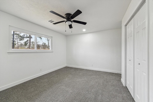 unfurnished bedroom featuring dark colored carpet, a closet, visible vents, and baseboards