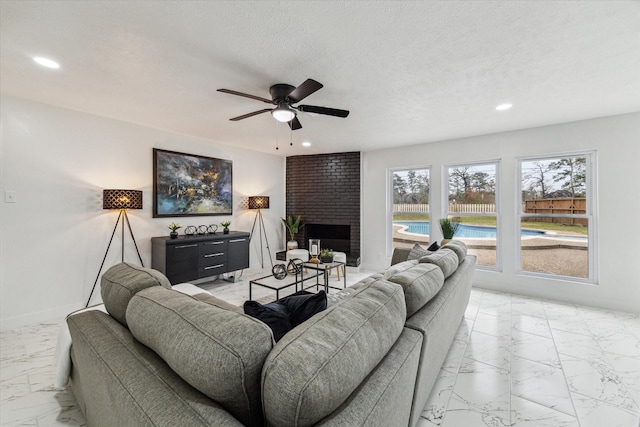 living room featuring a textured ceiling, marble finish floor, a fireplace, and recessed lighting