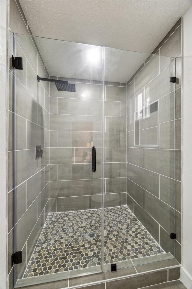 full bath with a stall shower and a textured ceiling