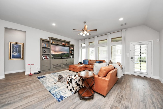 living area featuring visible vents, ceiling fan, vaulted ceiling, wood finished floors, and baseboards