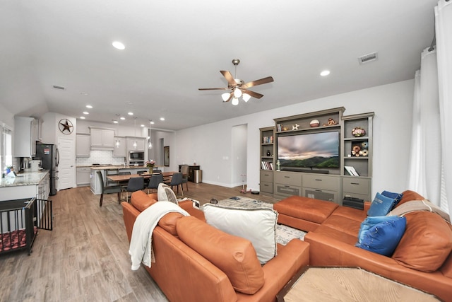 living area featuring light wood-style floors, visible vents, a ceiling fan, and recessed lighting