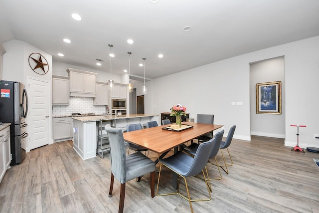 dining room with baseboards, light wood-style flooring, and recessed lighting