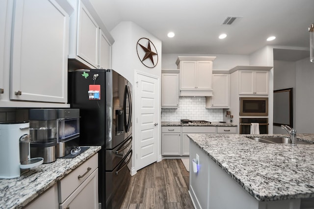 kitchen with recessed lighting, stainless steel appliances, a sink, decorative backsplash, and dark wood finished floors