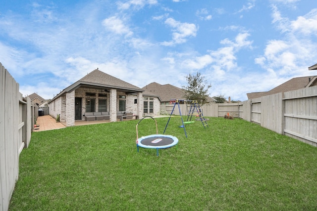 rear view of property with a playground, brick siding, a lawn, a patio area, and a fenced backyard