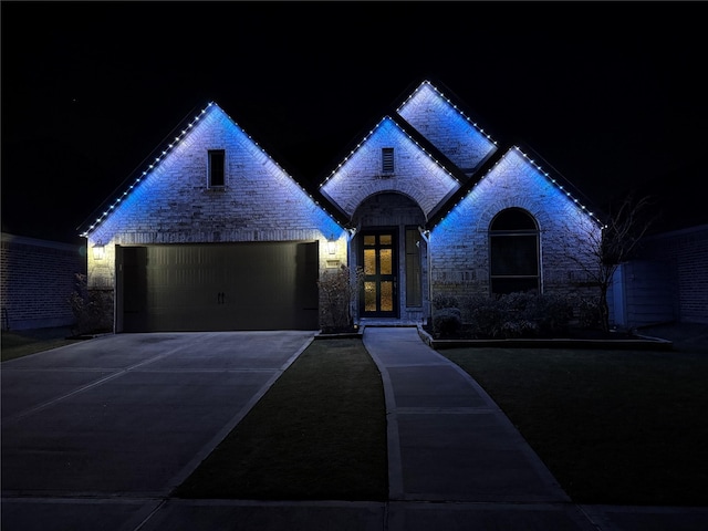 french country home with an attached garage and concrete driveway