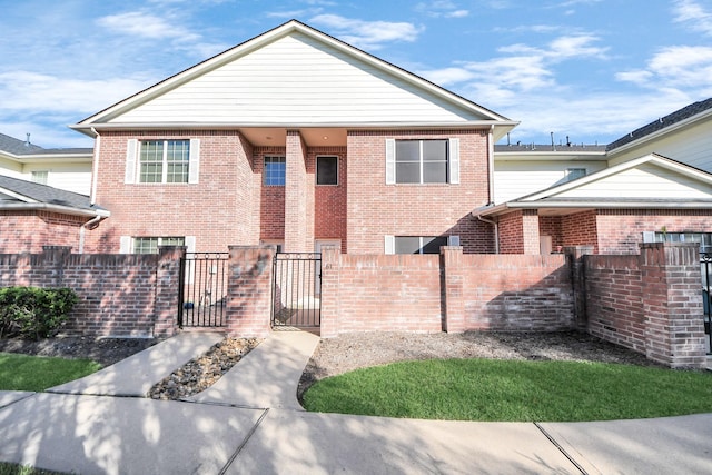 view of front of house featuring brick siding, a fenced front yard, and a gate