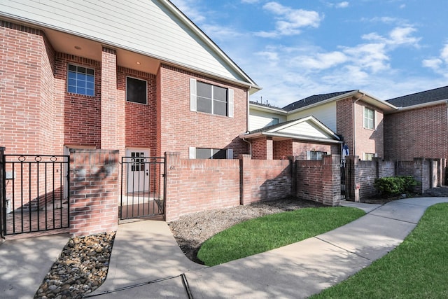 view of front of property featuring a fenced front yard, a gate, and brick siding