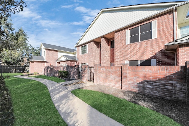 exterior space featuring fence, a lawn, and brick siding