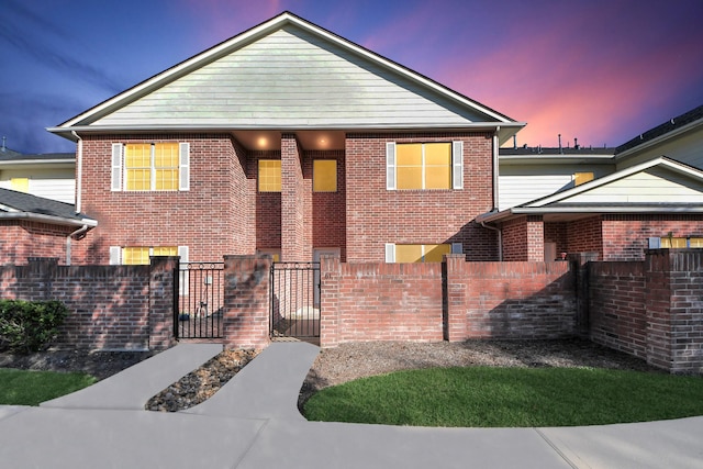 view of front of home featuring brick siding, a fenced front yard, and a gate