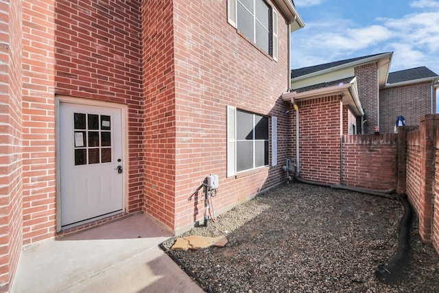 property entrance with brick siding and fence