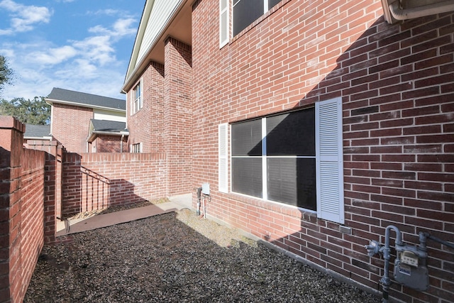 view of side of property with brick siding and fence