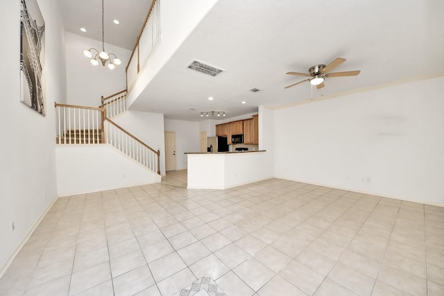 unfurnished living room featuring recessed lighting, ceiling fan with notable chandelier, a towering ceiling, visible vents, and stairway