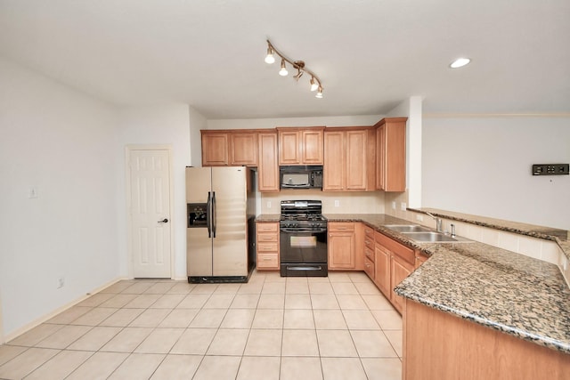 kitchen with light tile patterned floors, a peninsula, a sink, black appliances, and dark stone countertops