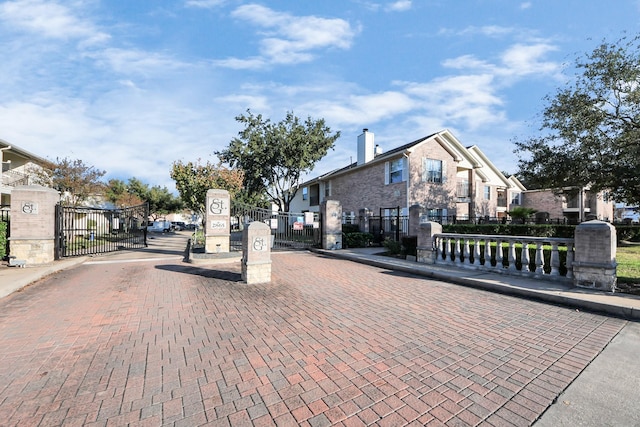 view of road featuring curbs, a gated entry, a residential view, and a gate