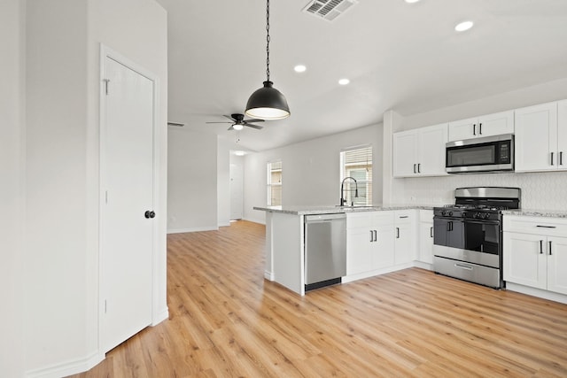 kitchen with a peninsula, visible vents, appliances with stainless steel finishes, and white cabinets