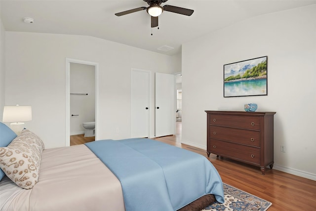 bedroom with ensuite bathroom, a ceiling fan, vaulted ceiling, wood finished floors, and baseboards