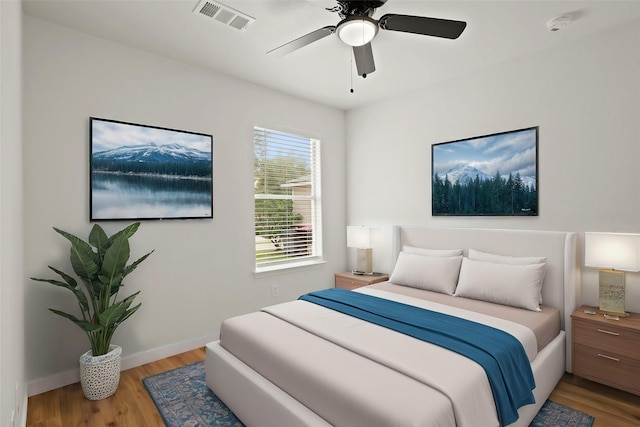 bedroom with a ceiling fan, visible vents, light wood-style flooring, and baseboards