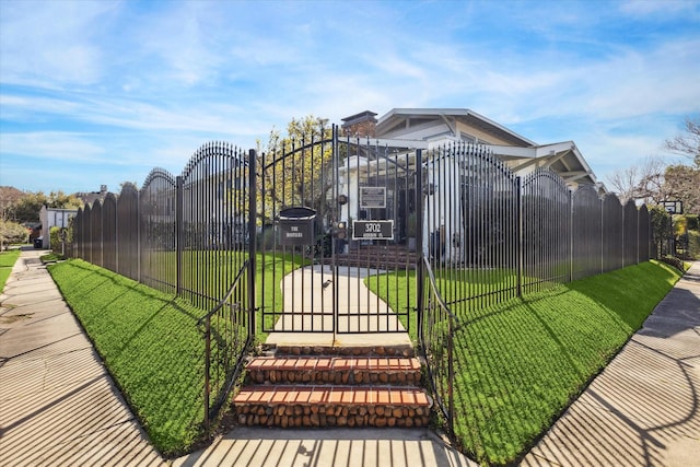 view of gate with a fenced front yard and a lawn