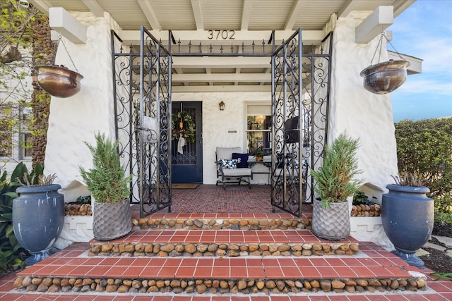 view of exterior entry featuring covered porch and stucco siding
