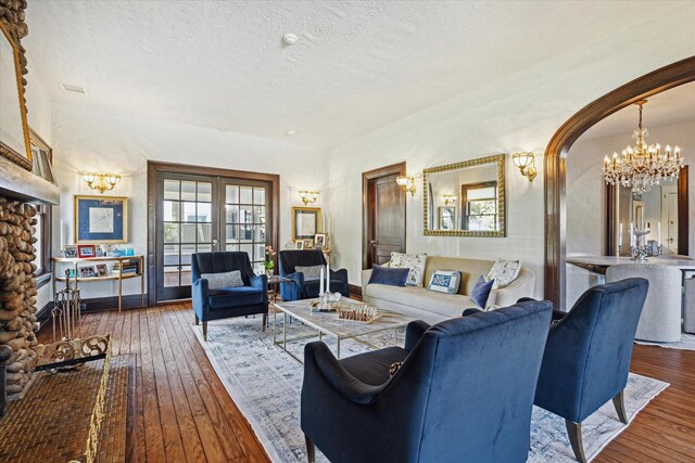 living area featuring hardwood / wood-style floors, arched walkways, an inviting chandelier, and a textured ceiling