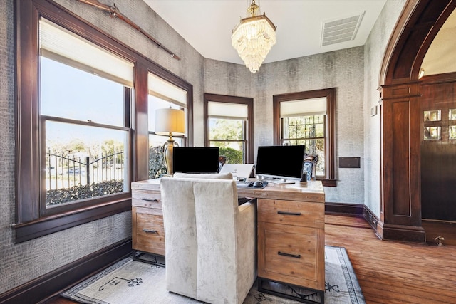 office area featuring an inviting chandelier, baseboards, wallpapered walls, light wood-type flooring, and visible vents