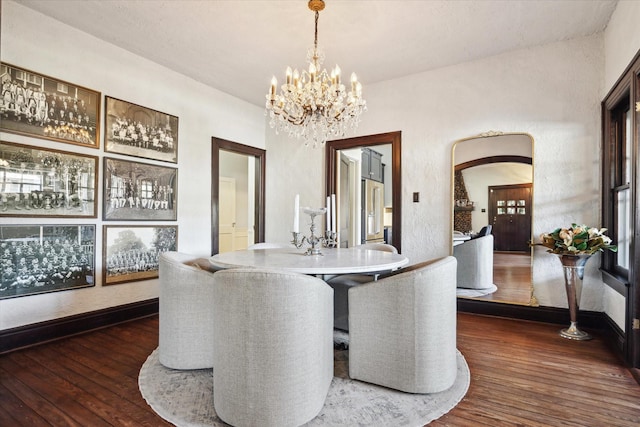 dining area with baseboards, arched walkways, a notable chandelier, and dark wood-style floors
