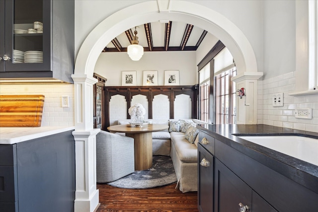 interior space with a sink, backsplash, dark wood finished floors, and beam ceiling