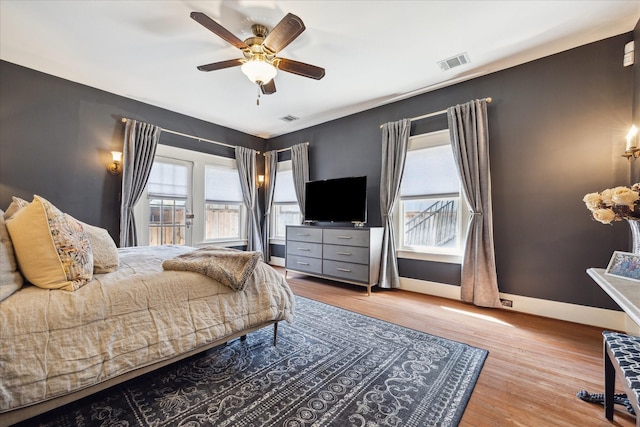 bedroom with visible vents, a ceiling fan, baseboards, and wood finished floors