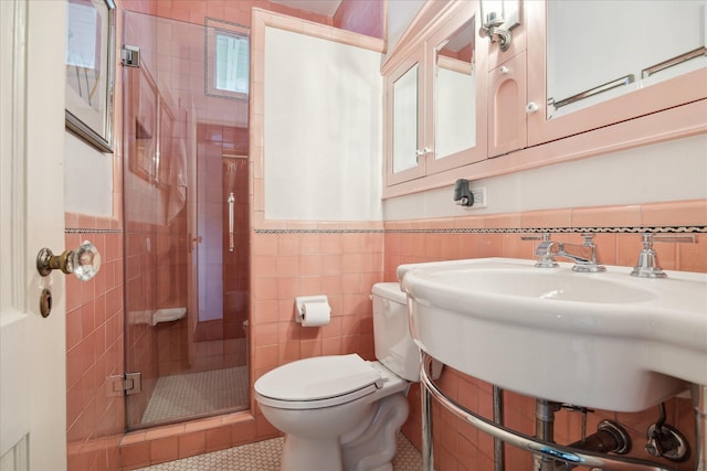 full bathroom featuring wainscoting, toilet, tile walls, tile patterned floors, and a stall shower