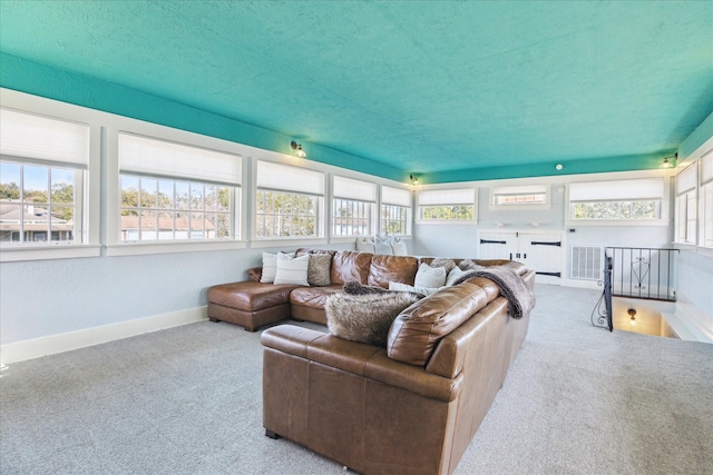 living room with carpet floors, a textured ceiling, baseboards, and visible vents