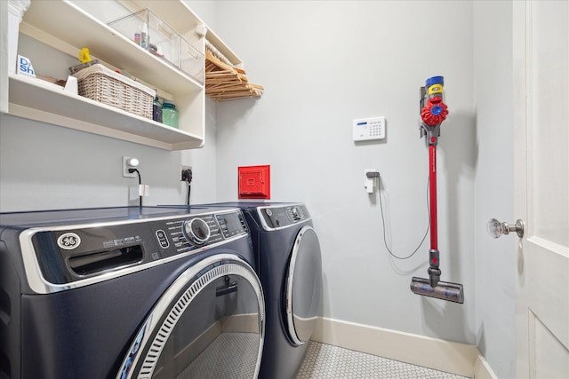 clothes washing area with laundry area, baseboards, and separate washer and dryer