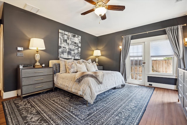 bedroom with visible vents, baseboards, access to outside, hardwood / wood-style flooring, and a ceiling fan