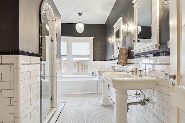 bathroom featuring tile patterned flooring, a sink, tile walls, and a shower stall