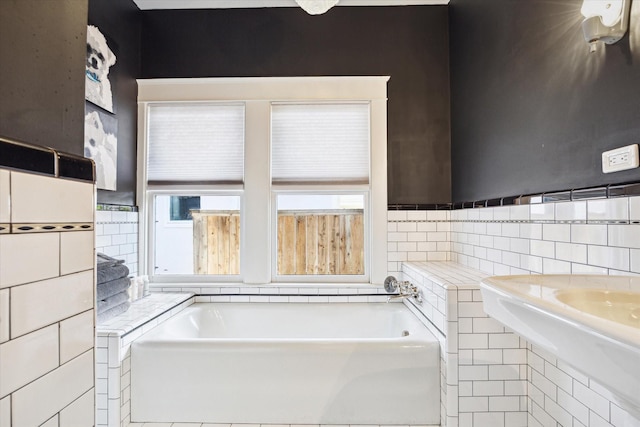 full bathroom with a garden tub, a sink, and tile walls