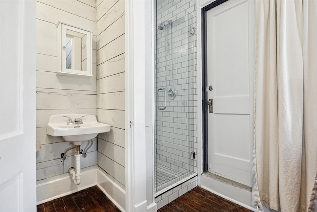 full bath with wood finished floors, wood walls, and a stall shower